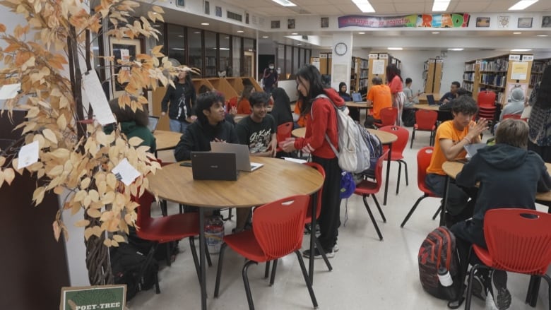 Students sitting around tables in a large room.