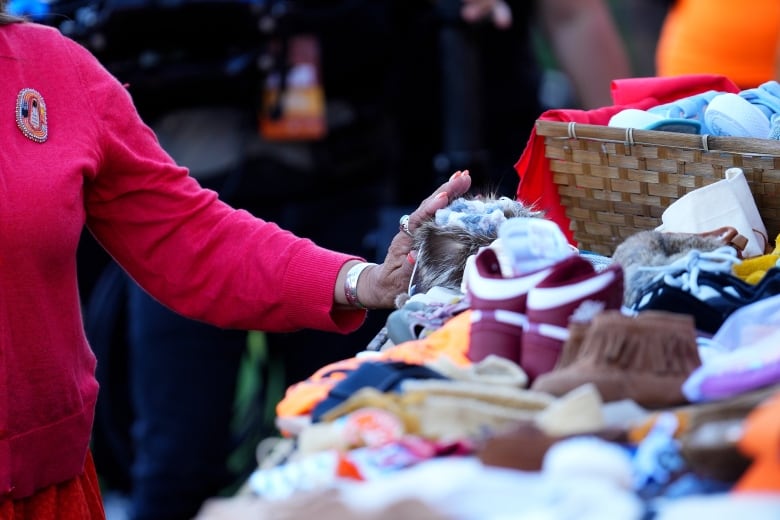 An attendee places children's shoes in memory of victims of Canada's residential school system during a ceremony on Truth and Reconciliation Day, in Ottawa, Monday, Sept. 30, 2024.