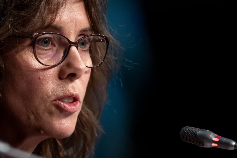 A woman in glasses in front of a microphone