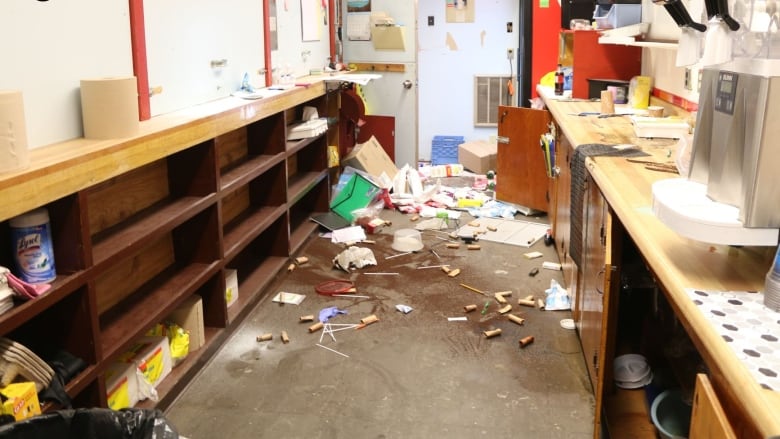 A corridor that looks messy, clearly vandalized, stuff all over the floor.