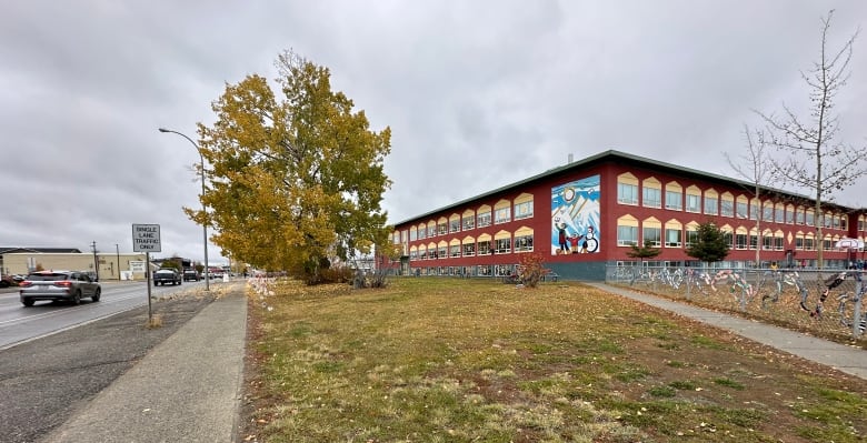 A red school building beside a city street.