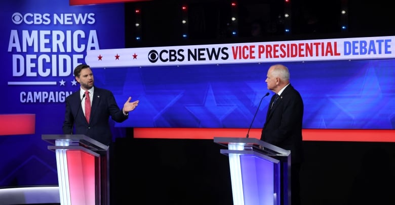 Two men in suits stand behind podiums. The sign behind them says, 