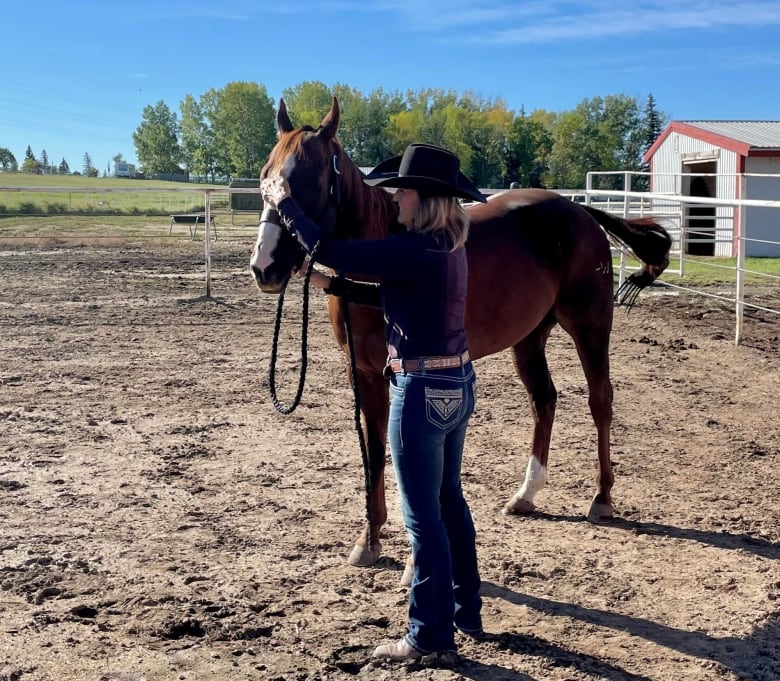 A woman strokes a horse's nose.