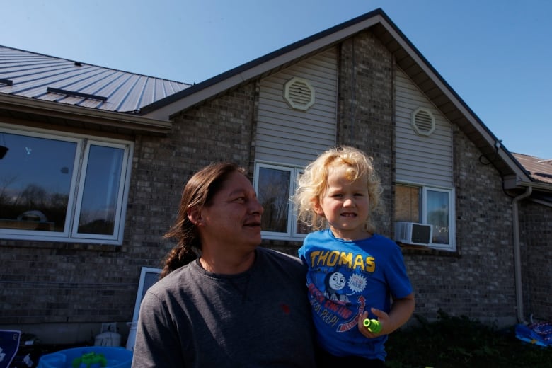 Jason Plain holds his grandson Teo before leaving with his family members during a voluntary evacuation of the Aamjiwnaang First Nation, near Sarnia, Ont., on Oct. 1, 2024. The nearby Ineos Styrolution plant is removing benzene from a storage tank as part of the plants dissolution.