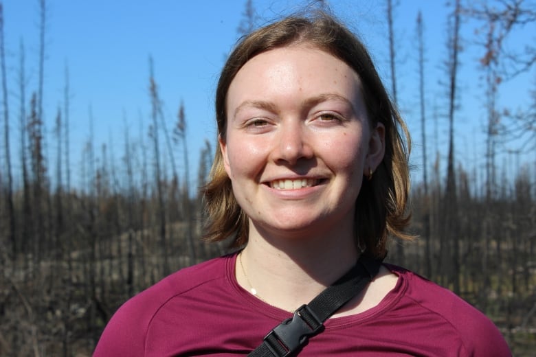 A woman in a red shirt and short blond hair smiling.