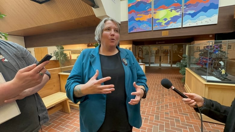 A woman speaks to reporters in a media scrum. 