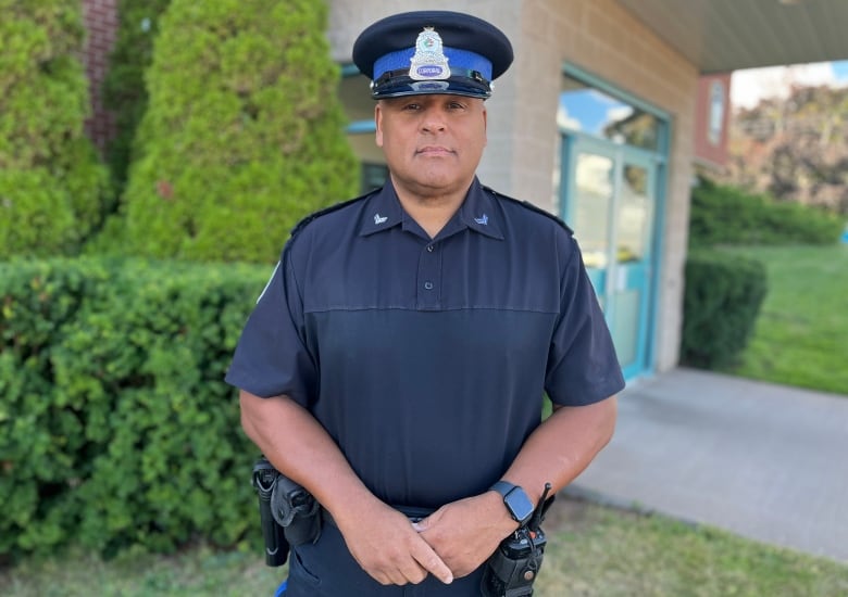 A man in a police uniform stands in front of a building.