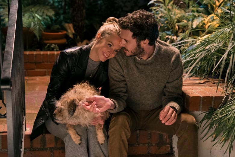 A man and woman embrace on a stoop