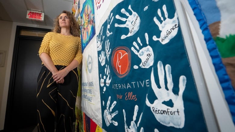 Woman leans against wall at centre for victims of intimate partner violence