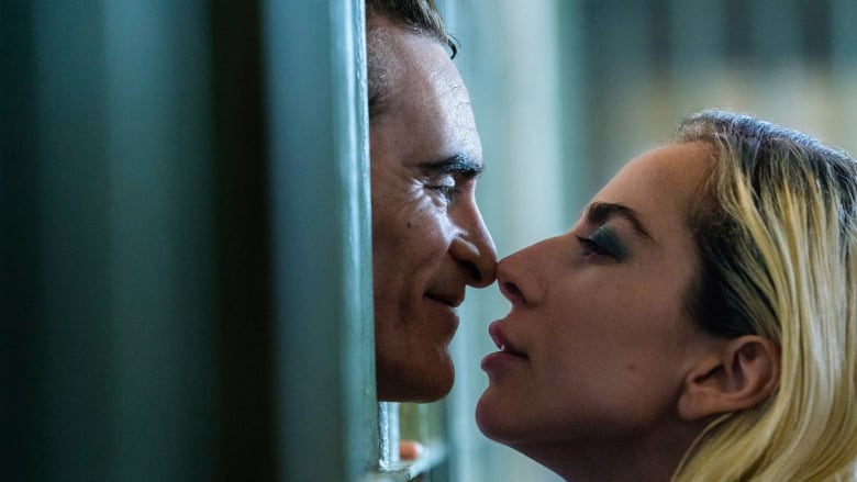 A smiling man pokes his head through prison bars, while a woman on the outside leans in close.