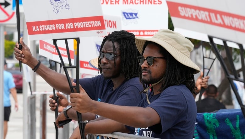 Two men stand side by side, holding signs that say 