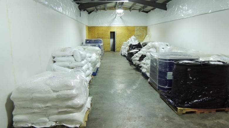 A room with piles of bags on the left and right side in white and black bags. 