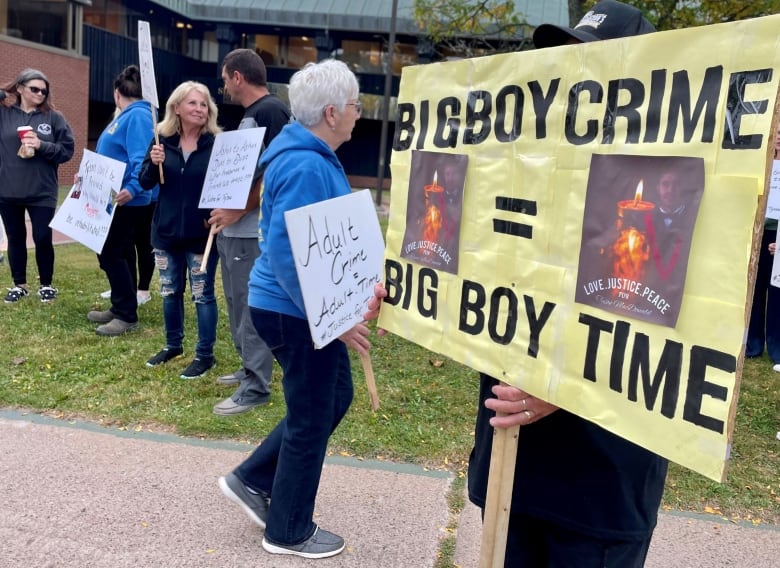 A person holds a sign reading 