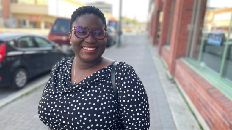 A smiling Black woman wearing red glasses.