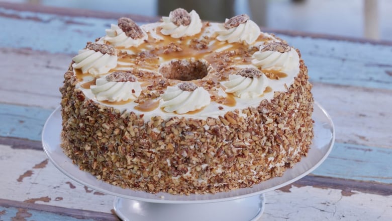 A tale ring cake covered in candied pecans, whipped cream and drizzled with caramel sauce.