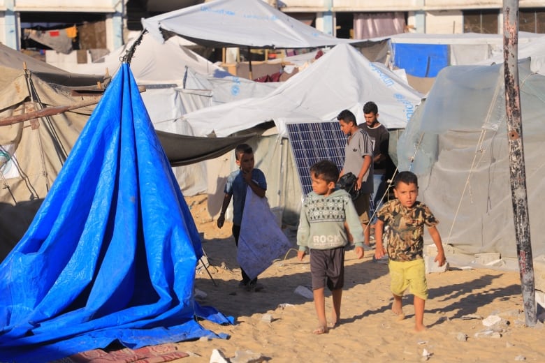 Children walk next to tents.