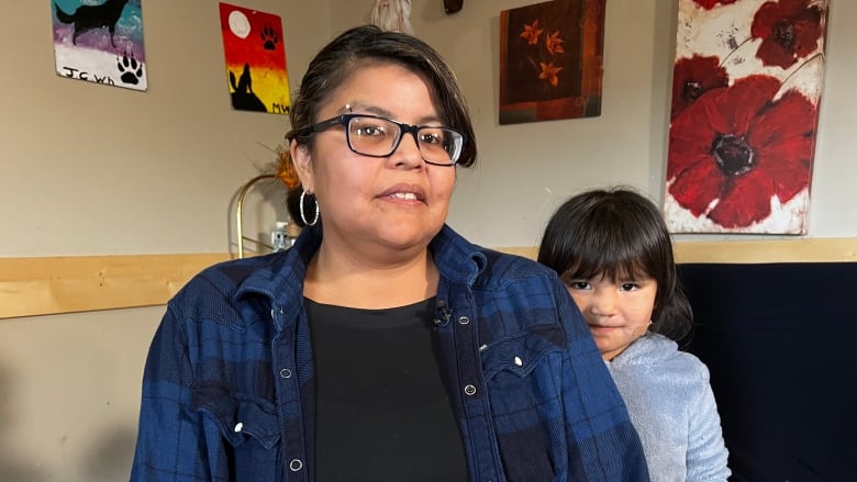 A woman in a blue plaid shirt beside her daughter, dressed in a fluffy hoodie