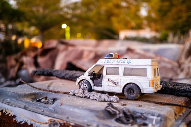 A toy ambulance is seen atop of some debris.