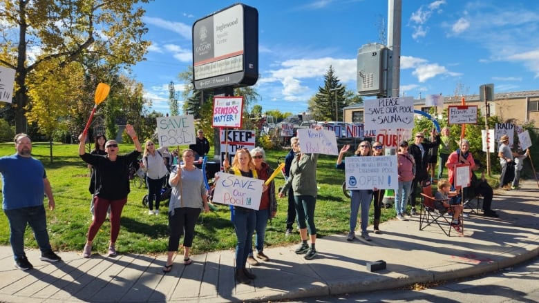 A group of people hold various signs calling to keep the Inglewood pool open.