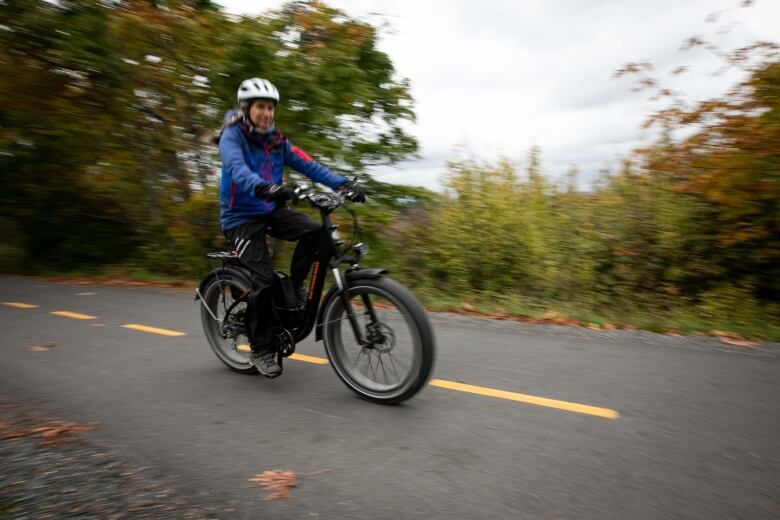 A person rides a black e-bike down a trail.