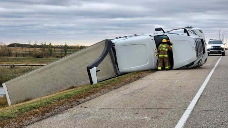 A semi-truck is tipped over on a highway.