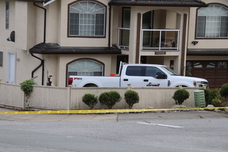 A white pickup truck lies behind fencing and crime tape.