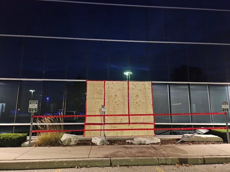 Boarded up windows and mangled parking signs shown at the back of the CAS building in Windsor, Ont.