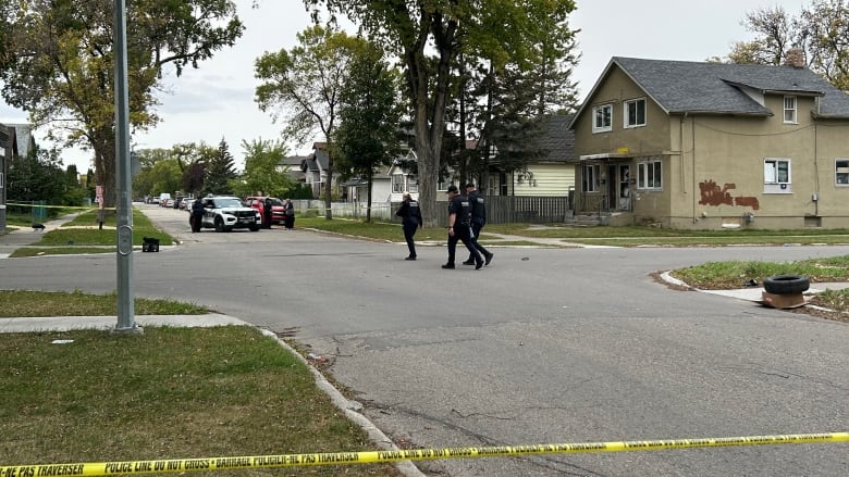 Police officers walk toward a police vehicle at an intersection. 