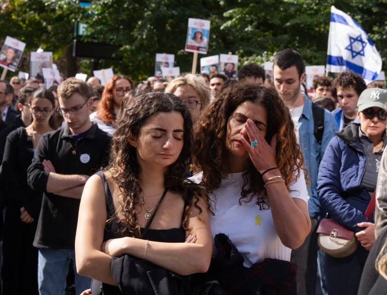 Two women crying in front of a crowd of people. 