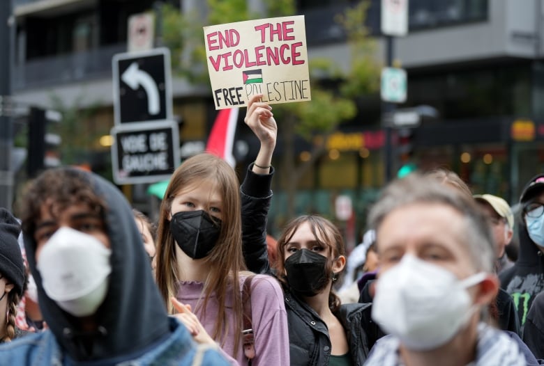 Women hold up sign in crowd.