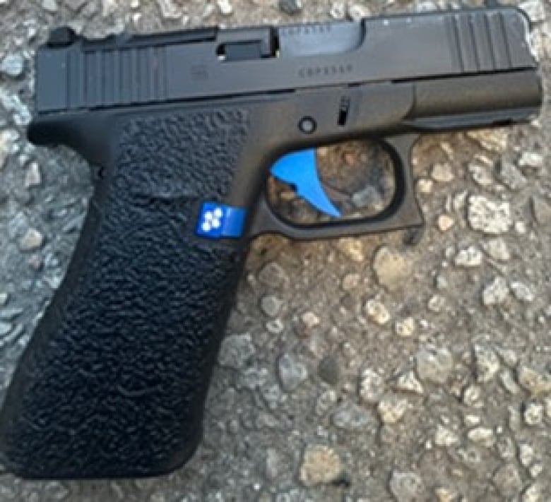 A black handgun laid out on a rocky surface 