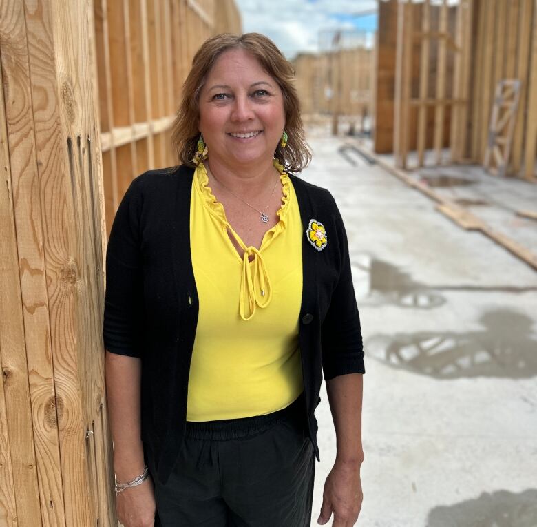 A woman standing in front of lumber framework for a building.