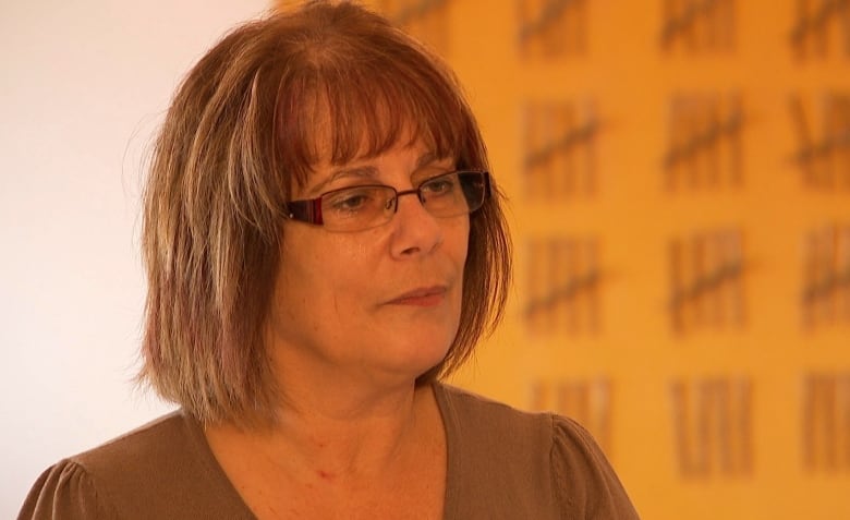 Woman with brown hair and glasses.