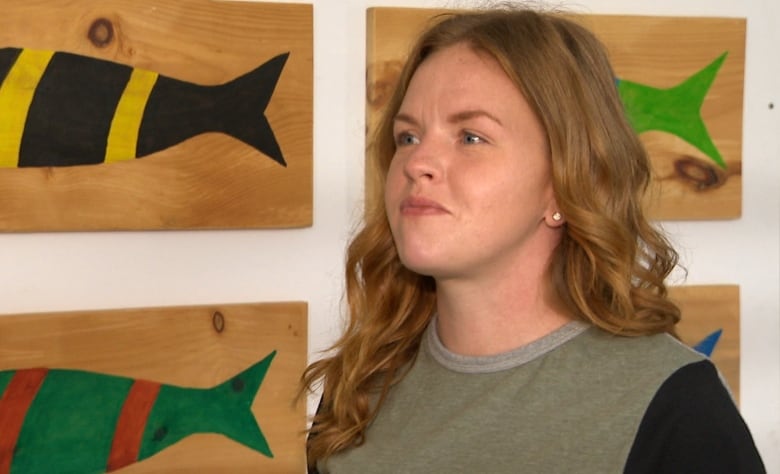 Girl with long hair in front of fish paintings. 