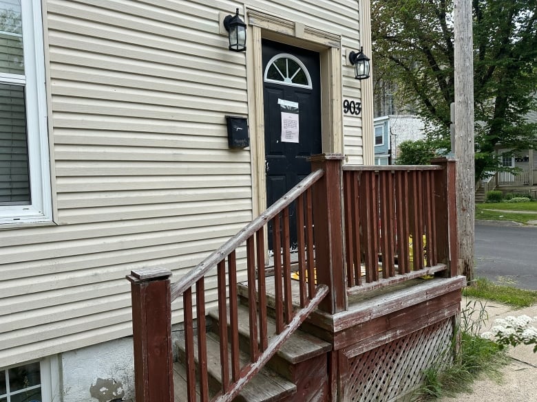 The front door of a small building with beige siding is shown.