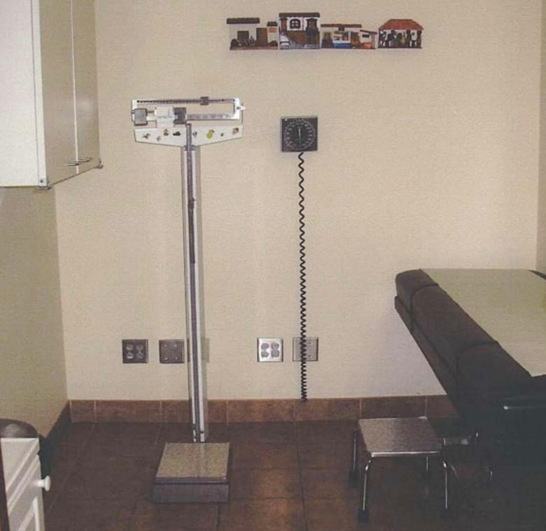 A doctors examination room with a scale and examination table.