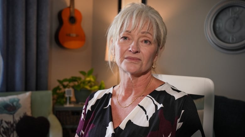 Photo of a woman sitting on chair looking directly into the camera. 