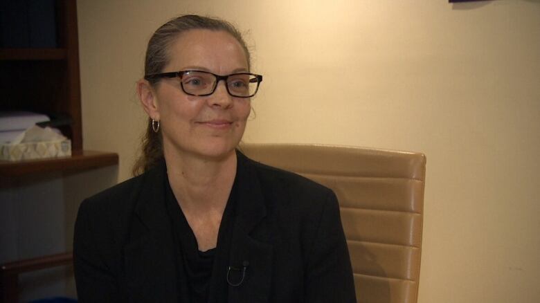 A smiling woman with glasses wearing a black shirt.