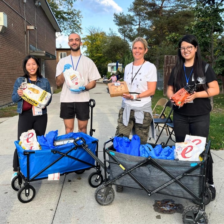 People stand with a cart holding food. 