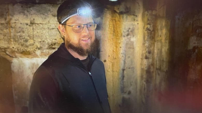 A man smiles while wearing a headlight.