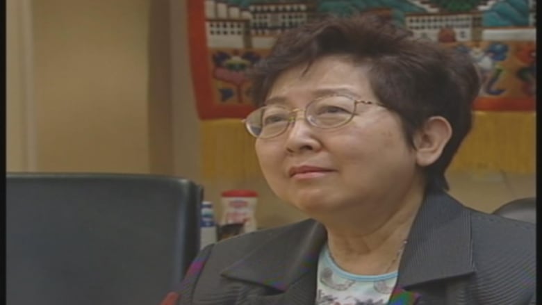 An East Asian woman talks into a television camera in an office.