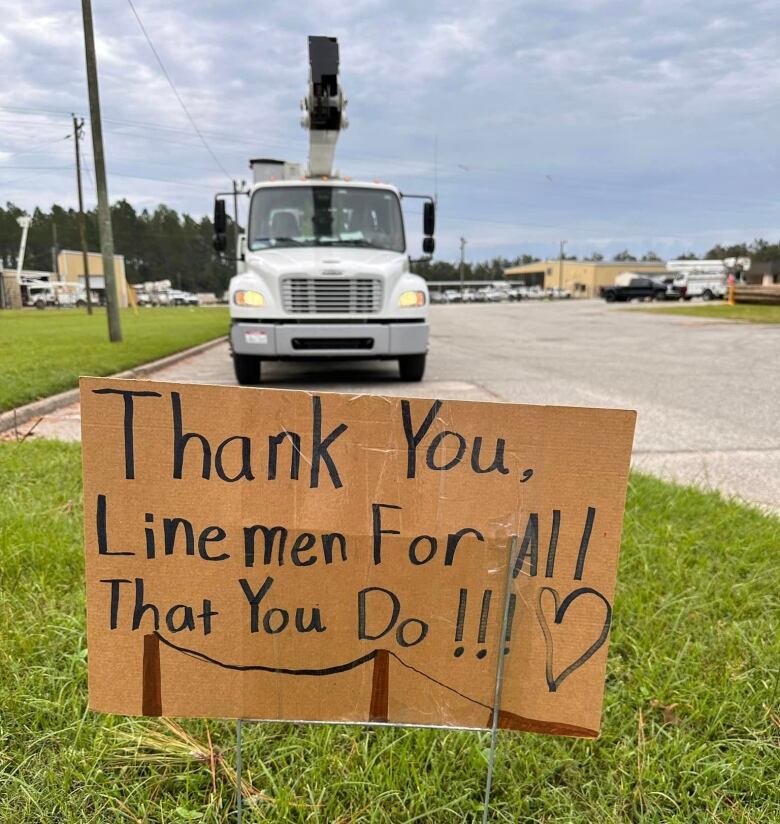 A sign placed on grass that thanks line-workers, with writing 