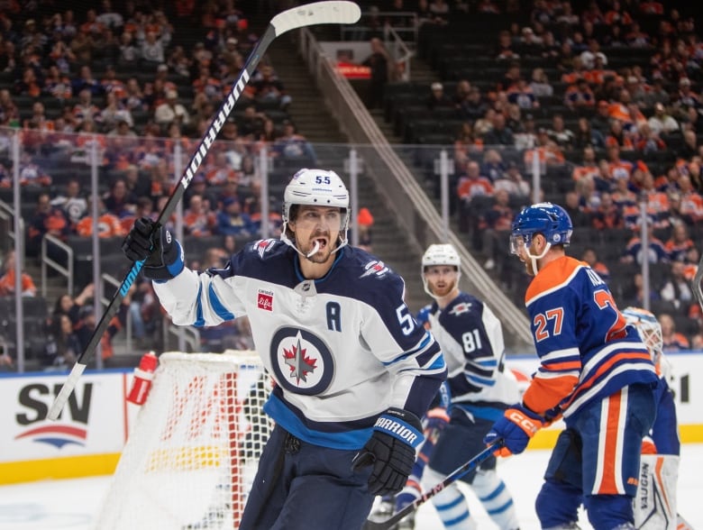 A hockey player raises his stick in celebration after a goal.