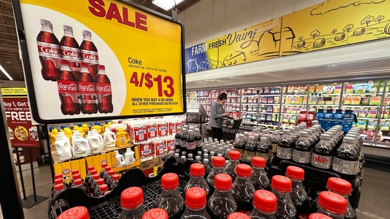 A pallet of plastic Coke brand bottles with red caps is visible underneath a 