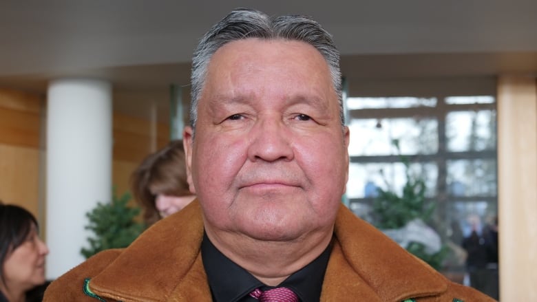 A portrait of a man in a beaded jacket.