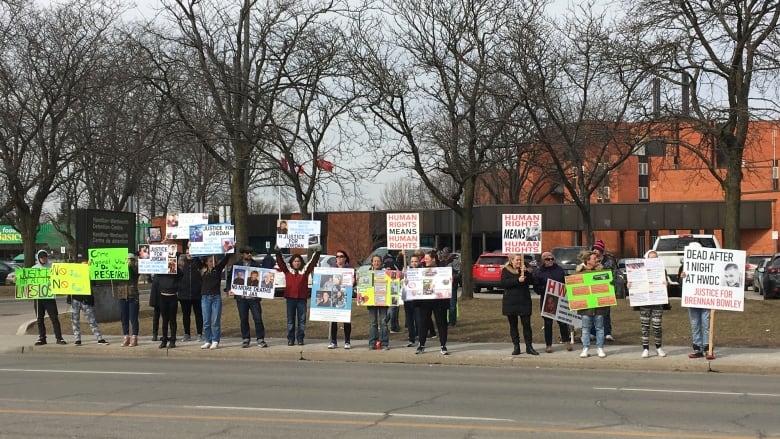 A line of people on a sidewalk with picket signs. 