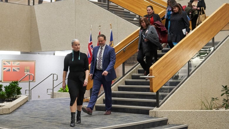 Six people walk down a flight of stairs.