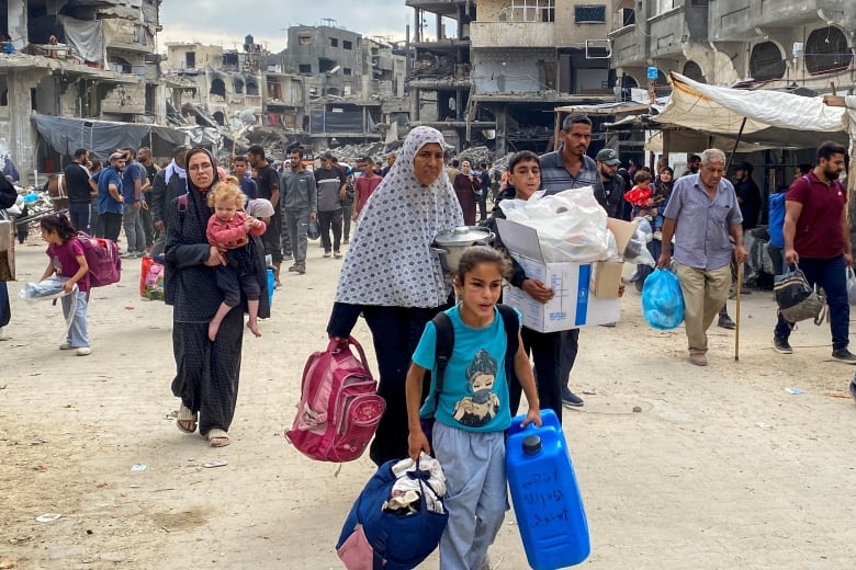 People flee an area in Gaza with bags in hand.