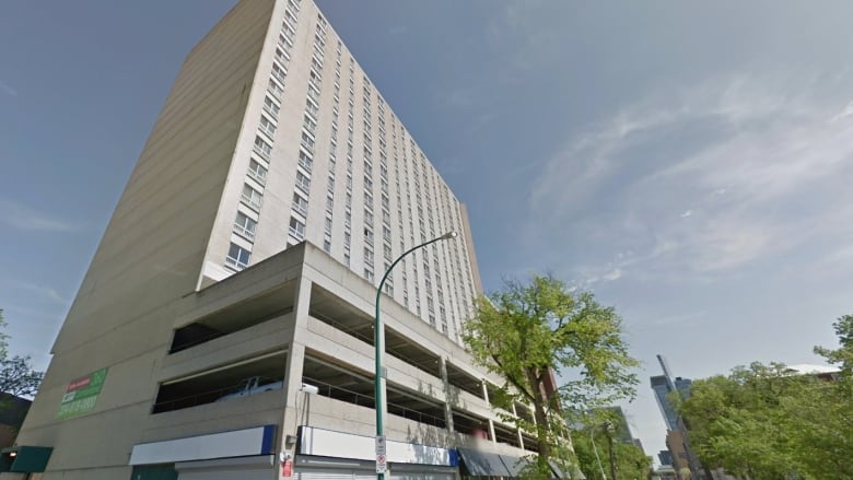 A tall apartment building is in the foreground of a photo from the street