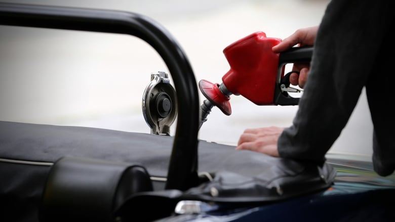 A close-up of a person filling their gas tank at a gas station.